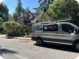 Professional roof cleaning service van parked on a quiet residential street in front of a home.